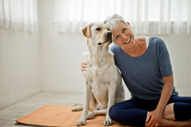 Happy woman with dog on yoga mat