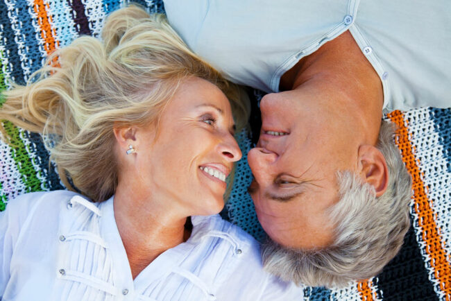 Older couple on beach blanket looking at each other