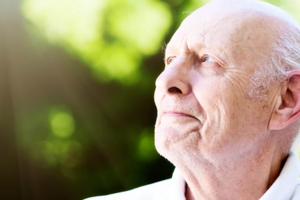 Old man with eye trouble squints up at sun