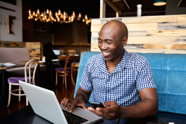 Middle-aged man in restaurant on phone and computer