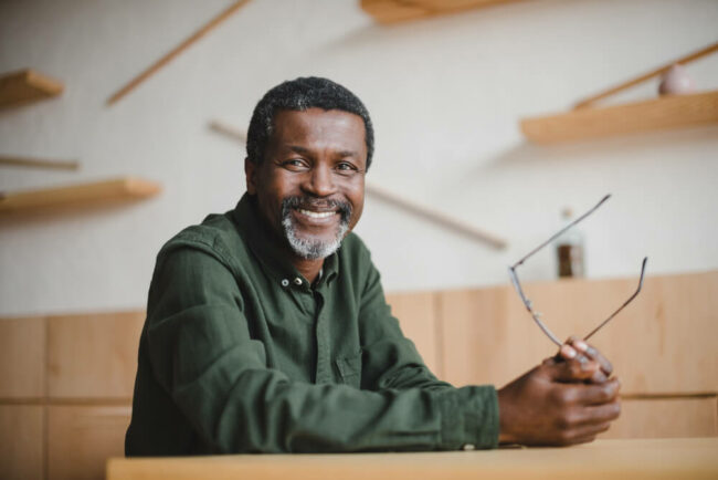 Middle-aged man smiling and holding glasses