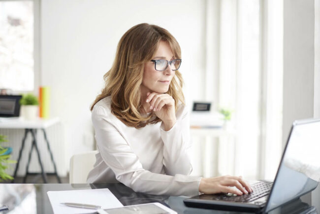 Middle-aged woman wearing glasses and looking at computer