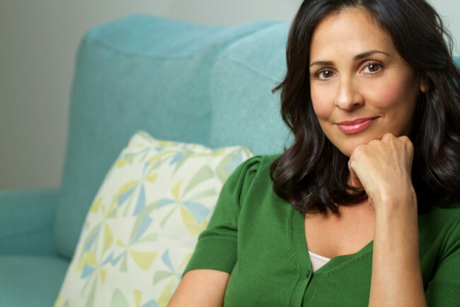 Middle-aged woman sitting on couch with hand on chin