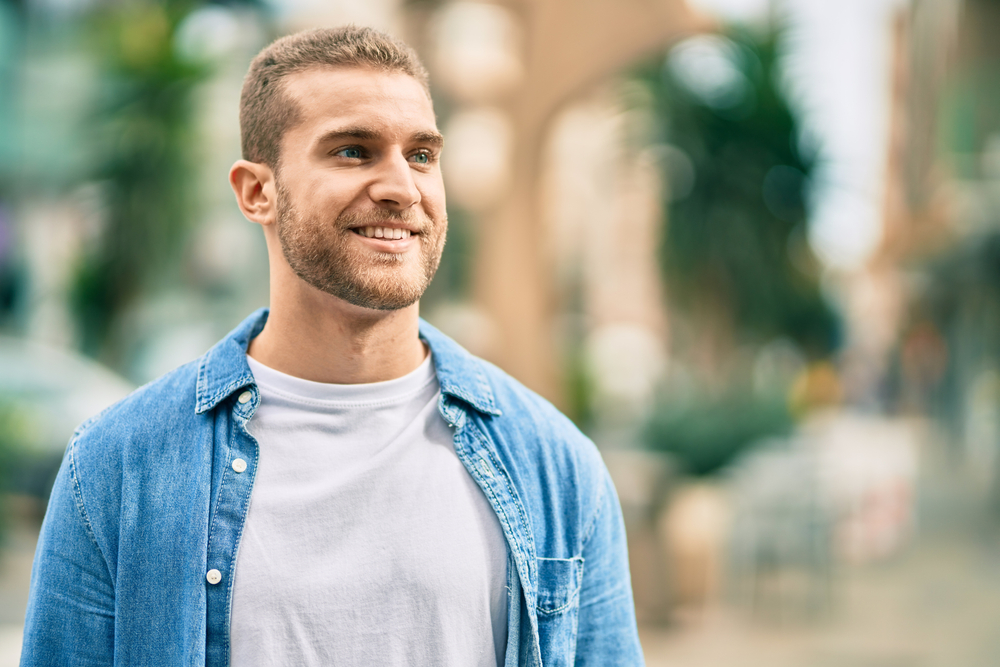 Man smiling outside in denim shirt